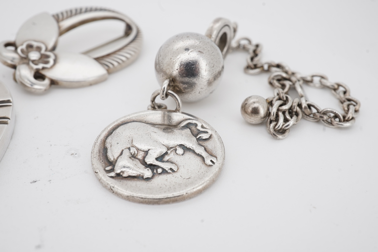 A Danish Georg Jensen sterling twin dolphin brooch, 40mm and a similar flower brooch, design numbers 317 and 227, a 1960's Georg Jensen silver bracelet, design no.46 and a similar 1970's silver heart pendant, design no.4